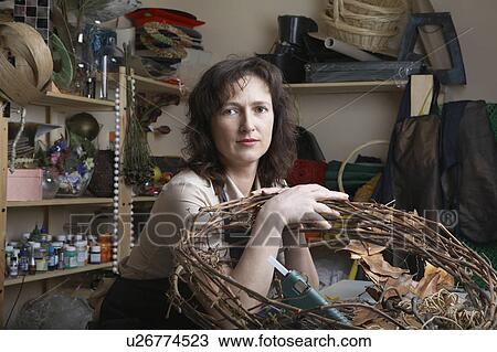 Stock Image - Florist in shop with wreath, portrait. Fotosearch