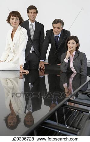 Stock Photo - Four business colleagues at conference table, portrait. Fotosearch