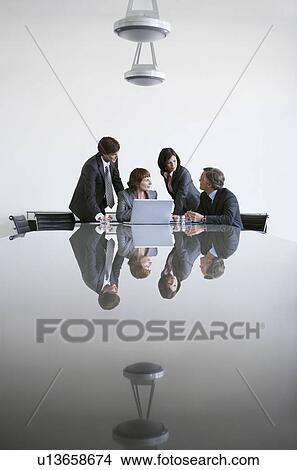 Four business colleagues using laptop at conference table View Large Photo Image Picture - Four business colleagues using laptop at conference table. Fotosearch