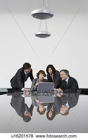Four business colleagues using laptop at conference table View Large Photo Image Stock Photo - Four business colleagues using laptop at conference table. Fotosearch
