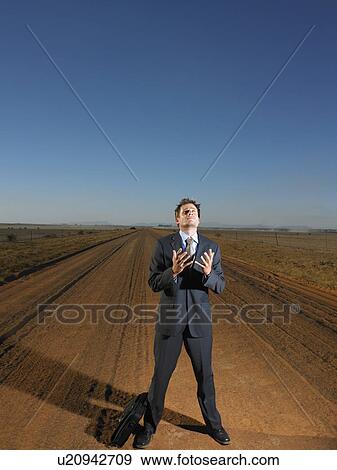 Stock Photo - Frustrated busiessman in middle of deserted road. Fotosearch