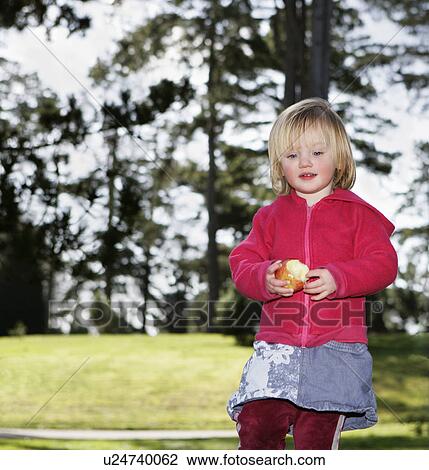 Girl (3-4) with apple outdoors View Large Photo Image Stock Image - Girl (3-4) with apple outdoors. Fotosearch