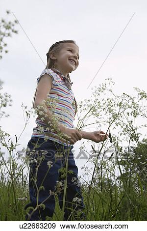 Stock Photo - Girl (5-6) playing in meadow. Fotosearch