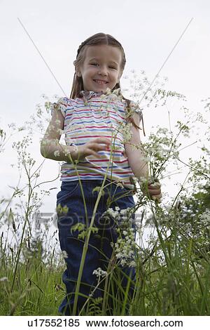 Stock Photography - Girl (5-6) standing in meadow, portrait. Fotosearch