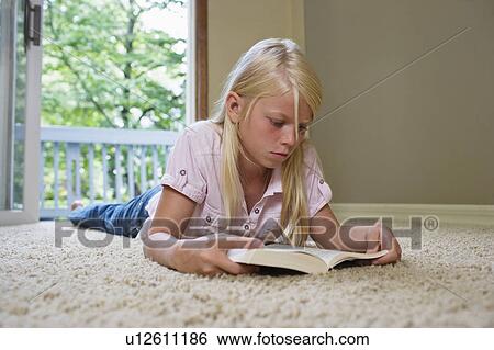 Girl (7-9) lying on carpet, reading book View Large Photo Image Stock Photograph - Girl (7-9) lying on carpet, reading book. Fotosearch