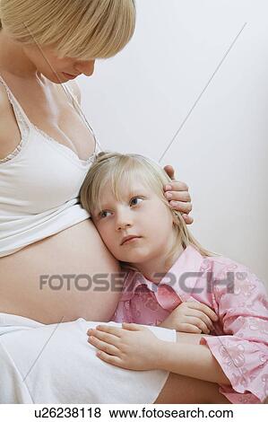 Girl (7-9) with ear to pregnant mother's belly View Large Photo Image Stock Photo - Girl (7-9) with ear to pregnant mother's belly. Fotosearch