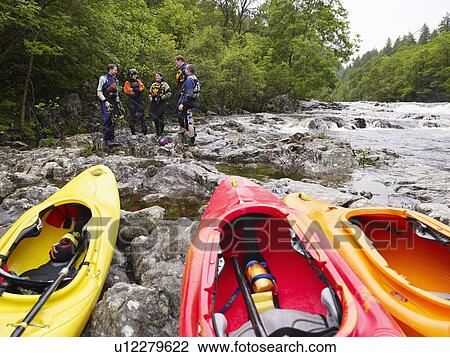 Group of people by river kayaks in foreground View Large Photo Image Stock Image - Group of people by river kayaks in foreground. Fotosearch