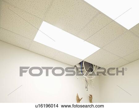 Picture - Hands reaching towards cable hanging from hole in ceiling. Fotosearch