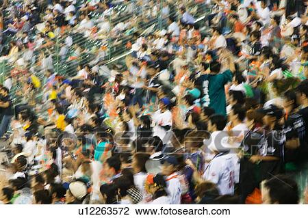 Stock Image - Japan, Kobe, Yahoo Stadium, crowd of people watching baseball match, motion blur. Fotosearch