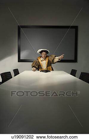 Stock Image - King Henry VIII pointing in conference room. Fotosearch