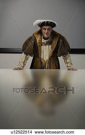 Picture - King Henry VIII standing at table in conference room. Fotosearch