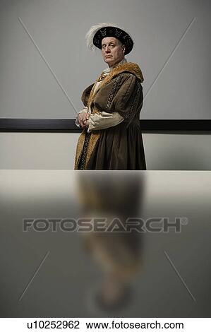 Stock Image - King Henry VIII standing at table in conference room, portrait. Fotosearch
