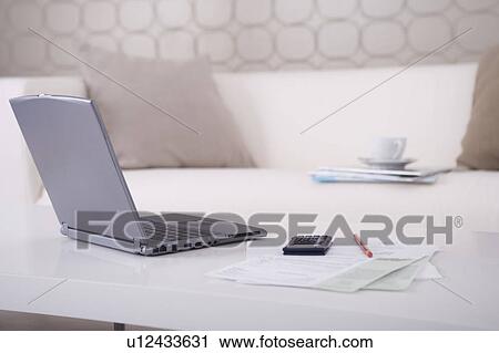 Stock Image - Laptop and paperwork on table. Fotosearch