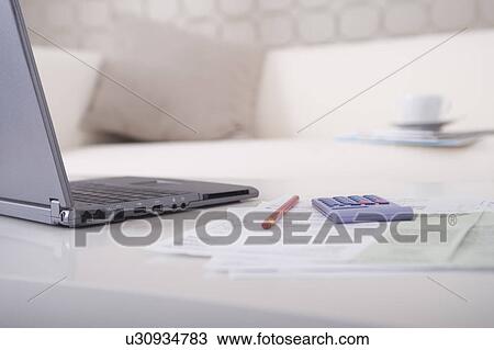 Stock Image - Laptop and paperwork on table. Fotosearch
