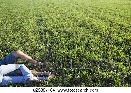 Picture - Legs of Young Couple Lying in Empty Field. Fotosearch
