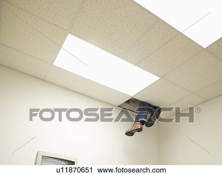Stock Image - Legs peeping from hole in ceiling. Fotosearch