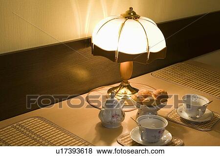 Lit lamp and teacups with scones View Large Photo Image Stock Photo - Lit lamp and teacups with scones. Fotosearch