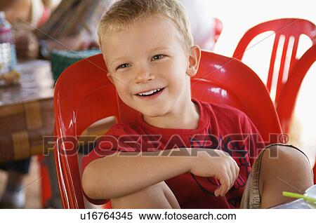 Stock Photography - Little Boy Sitting in Red Plastic Chair. Fotosearch