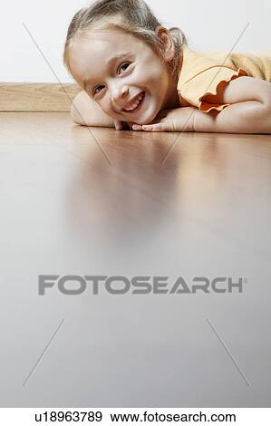 Stock Photo - Little Girl Lying on Wood Floor. Fotosearch