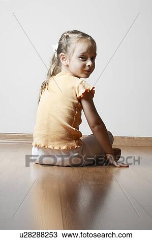 Stock Image - Little Girl Sitting on Wood Floor. Fotosearch