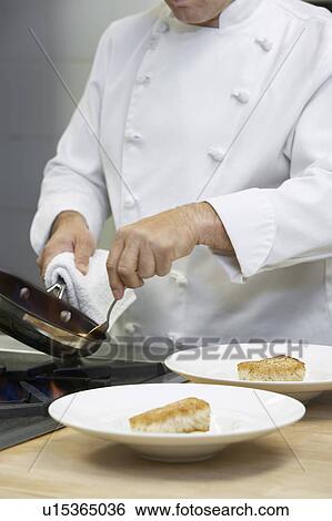 Male chef holding frying pan, serving food onto dishes in kitchen View Large Photo Image Stock Photograph - Male chef holding frying pan, serving food onto dishes in kitchen. Fotosearch