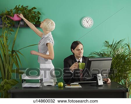 Man and woman in office, man at desk, woman watering plants View Large Photo Image Stock Image - Man and woman in office, man at desk, woman watering plants. Fotosearch
