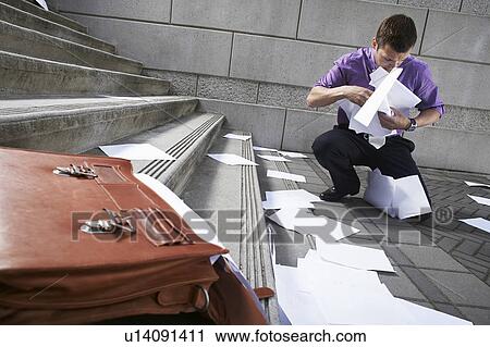 Stock Image - Man collecting spilled paperwork from steps. Fotosearch