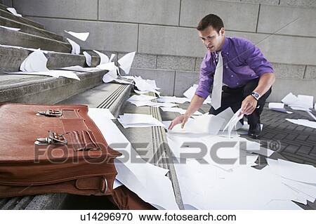 Stock Image - Man collecting spilled paperwork from steps. Fotosearch