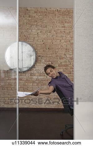 Picture - Man handing papers in office. Fotosearch