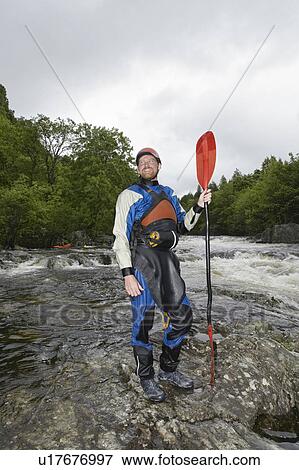 Stock Photo - Man holding kayak oar by river. Fotosearch