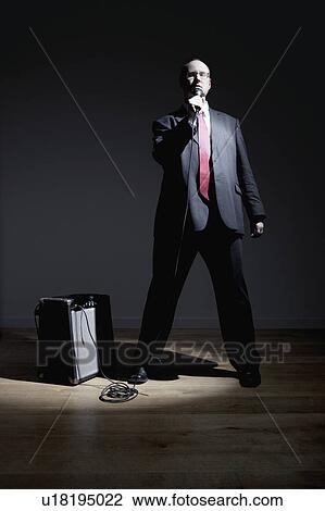 Stock Image - Man in full suit singing into microphone. Fotosearch