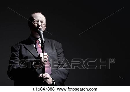 Man in full suit singing into microphone View Large Photo Image Stock Photo - Man in full suit singing into microphone. Fotosearch