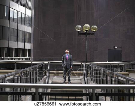 Stock Image - Man standing at top of steps, looking up. Fotosearch