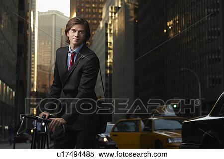 Man standing by bicycle in street View Large Photo Image Stock Photography - Man standing by bicycle in street. Fotosearch