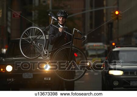 Man standing on street, carrying bicycle, portrait View Large Photo Image Stock Photo - Man standing on street, carrying bicycle, portrait. Fotosearch