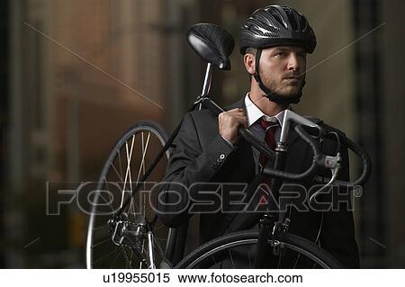 Man standing on street, carrying bicycle, portrait View Large Photo Image Stock Photography - Man standing on street, carrying bicycle, portrait. Fotosearch