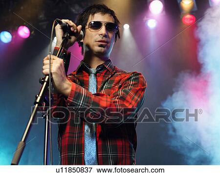 Man standing with microphone on stage at Concert, low angle view View Large Photo Image Stock Photo - Man standing with microphone on stage at Concert, low angle view. Fotosearch