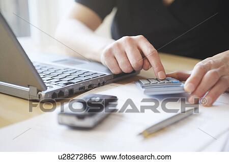 Man using calculator at desk, with laptop, cell phone and pen in foreground, close-up, mid section View Large Photo Image Stock Photography - Man using calculator at desk, with laptop, cell phone and pen in foreground, close-up, mid section. Fotosearch