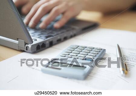 Man using laptop with calculator and pen in foreground, close-up View Large Photo Image Stock Image - Man using laptop with calculator and pen in foreground, close-up. Fotosearch