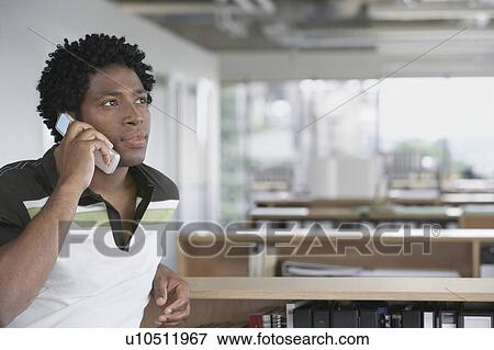Stock Photo - Man using mobile phone in office. Fotosearch