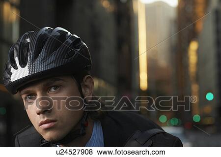 Stock Photo - Man wearing cycling helmet on street, close-up, portrait. Fotosearch