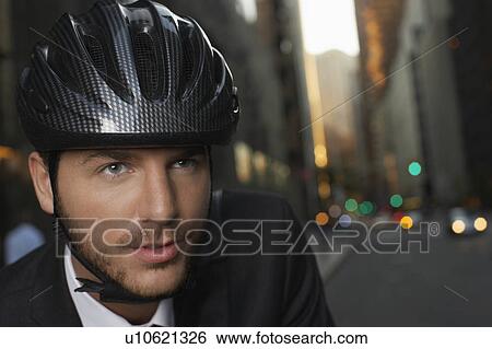Stock Photograph - Man wearing cycling helmet on street, close-up, portrait. Fotosearch