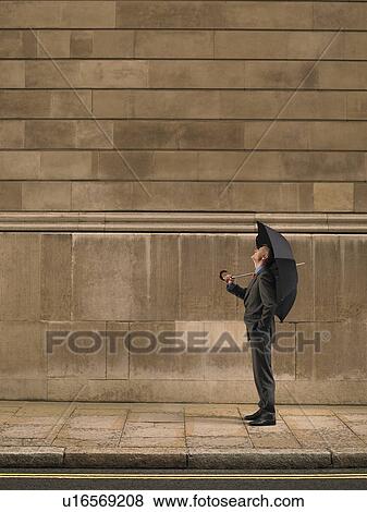 Man with umbrella on sidewalk, looking up View Large Photo Image Stock Photo - Man with umbrella on sidewalk, looking up. Fotosearch