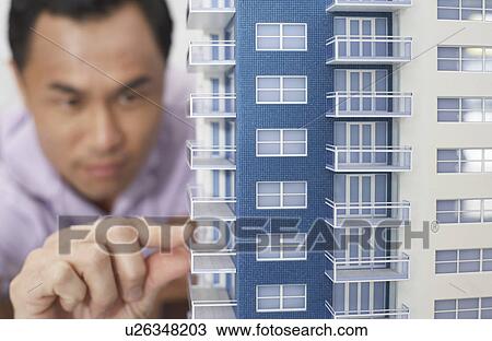 Stock Image - Mid adult man inspecting architectural model, close-up. Fotosearch