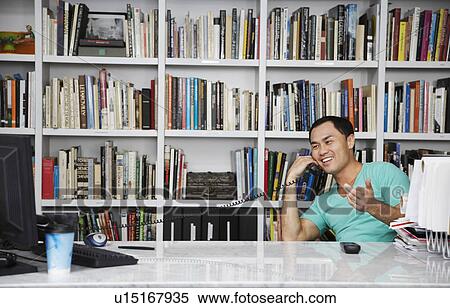 Mid adult man using phone in front of bookshelf View Large Photo Image Stock Photography - Mid adult man using phone in front of bookshelf. Fotosearch