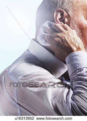 Stock Image - Middle Aged Businessman wiping sweat from back of neck, close-up, side view. Fotosearch