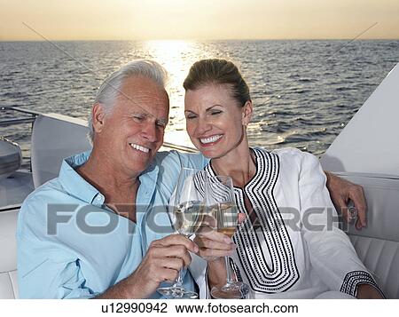 Stock Image - Middle-aged couple toasting with champagne. Fotosearch