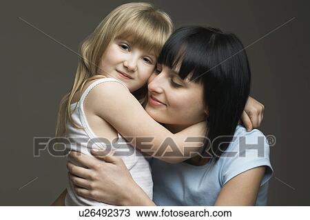 Stock Image - Mother and daughter (3-4) embracing, studio shot. Fotosearch