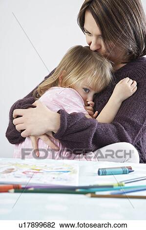 Stock Image - Mother embracing and kissing sad daughter (3-4). Fotosearch