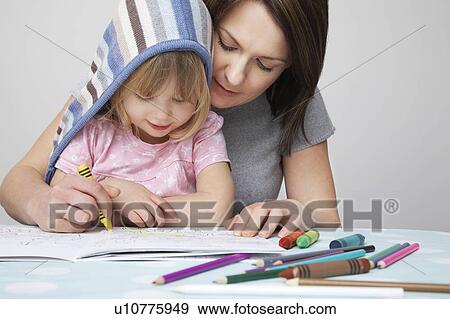 Stock Photo - Mother helping daughter (3-4) with colouring in book. Fotosearch
